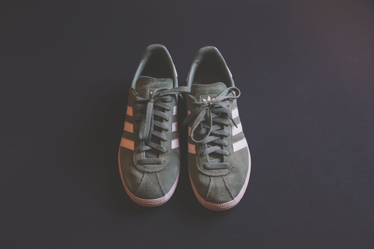 Stylish green sneakers with white stripes on a dark background, showcasing casual footwear.